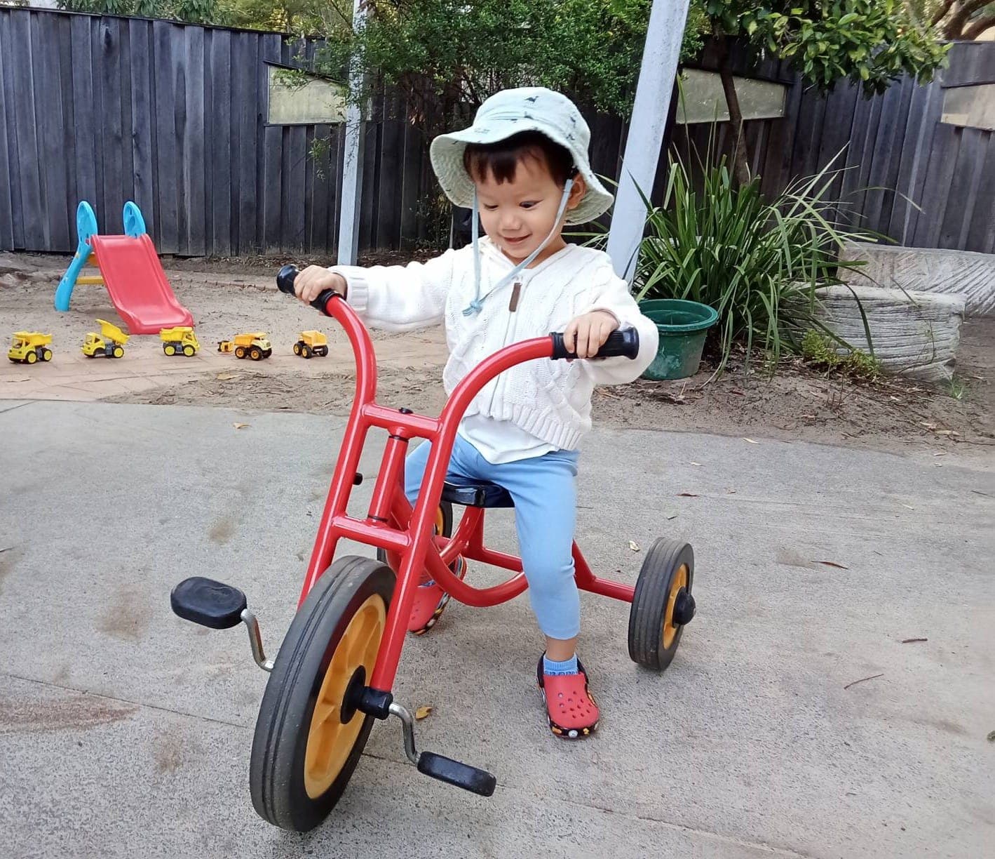 A child riding a tricycle outdoors at our St Lucia early learning centre